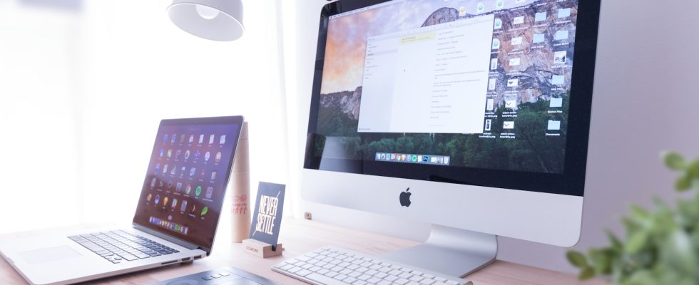 silver iMac near iPhone on brown wooden table